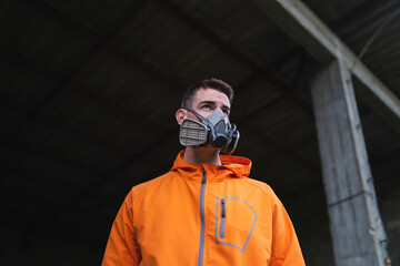 One young guy drawing graffiti on wall with spray can and mask on his face during the day