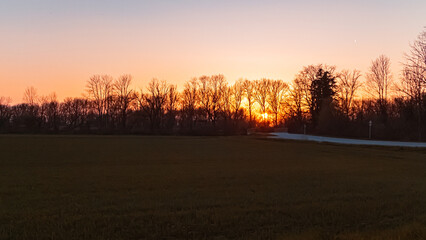 Fototapeta na wymiar Sunset with tree silhouettes near Plattling, Isar, Bavaria, Germany