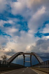 Winter landscape with dramatic clouds and a bridge on a sunny day near Plattling, Isar, Deggendorf, Bavaria, Germany