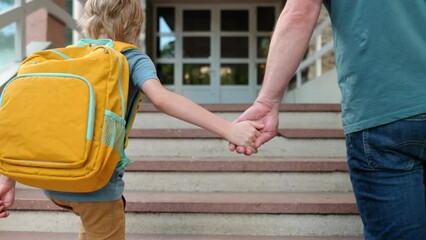 Little schoolboy with his father goes to school after summer holiday. Parent accompanies or meets the child. Quality education for children. Kids back to school concept.