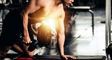 Man wearing red shirt lifting dumbbells in the gym, fitness gym, healthy exercise guidelines concept.