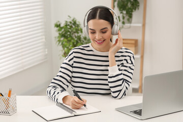 Obraz premium Online translation course. Student in headphones writing near laptop at home