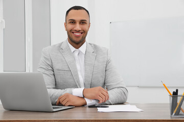 Happy young intern working at table in modern office