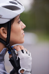 Making sure its on tight. A young cyclist fastening her helmet.