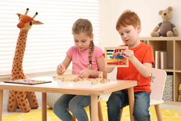 Children playing with different math game kits at desk in room. Study mathematics with pleasure
