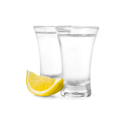 Shot glasses of vodka with lemon slice on white background