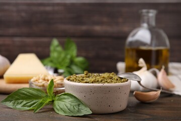 Tasty pesto sauce and ingredients on wooden table, closeup