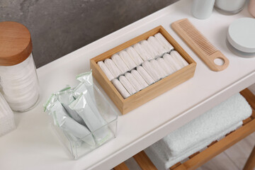 Many different tampons and personal care products on white table near grey wall, above view