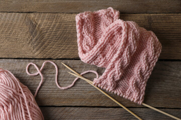Fototapeta na wymiar Soft pink woolen yarn, knitting and needles on wooden table, flat lay