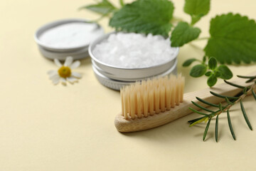 Fototapeta na wymiar Bamboo toothbrush and herbs on beige background, closeup. Space for text