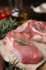 Fresh raw meat with rosemary on parchment paper, closeup