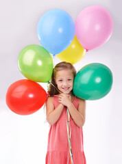 Fototapeta na wymiar Every childs favorite. Studio portrait of an adorable little girl holding colorful balloons.