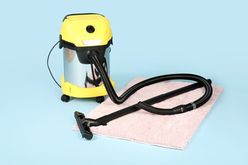 Vacuum cleaner with carpet on blue background