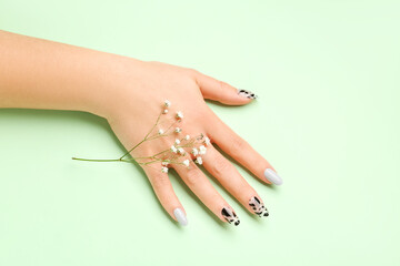 Woman with press-on nails and flowers on green background