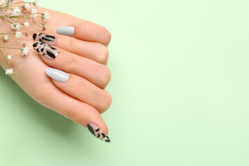 Woman with press-on nails and flowers on green background, closeup