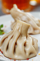 Georgian dumplings Khinkali with meat, greens and tomato spicy sauce Satsebeli on white plate