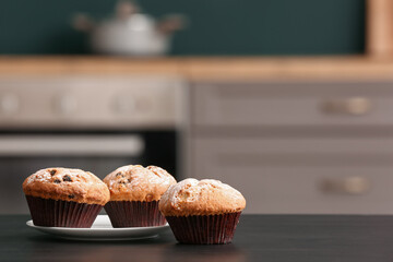 Plate with delicious muffins on black table in kitchen