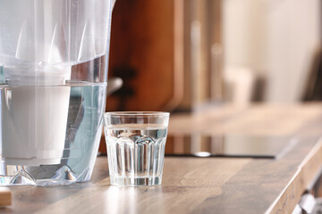 Filter jug and glass of water on kitchen counter, closeup