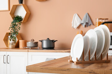 Dish rack with clean plates on wooden kitchen counter