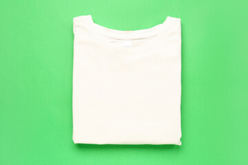Folded white t-shirt on green background