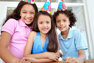 Celebrating a friends birthday. Portrait of three young children at a birthday party.