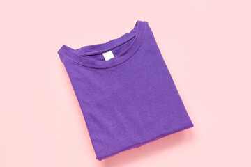 Folded purple t-shirt on pink background