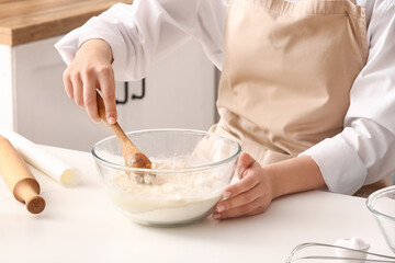 Woman making dough for Italian Grissini at white table in kitchen