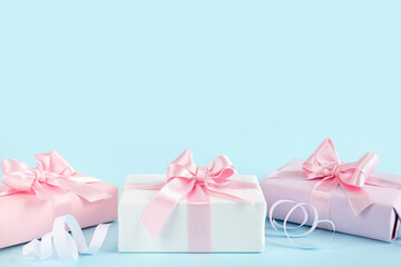 Gift boxes with beautiful bows and serpentine on blue background
