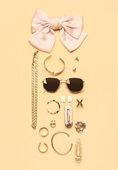 Stylish jewelry with sunglasses on beige background