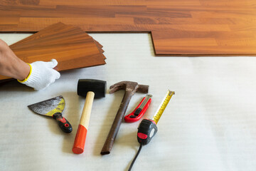 Man installing new laminated wooden floor,  Construction instruments .