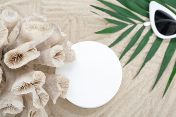 Obraz na płótnie Canvas Decorative plaster podium, coral, sunglasses and palm leaves in sand