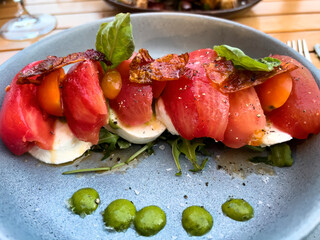 Healthy salad made of cheese, tomato, bacon, spinach, and basil