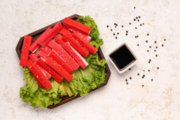 Plate with tasty crab sticks and sauce on light background © Pixel-Shot