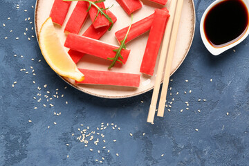 Plate with tasty crab sticks and sauce on blue background © Pixel-Shot