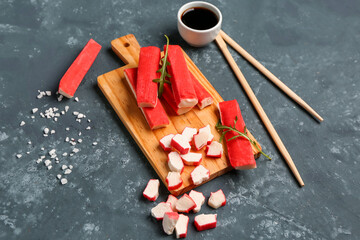 Wooden board with tasty crab sticks on green background © Pixel-Shot