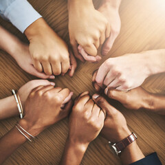 Drawing strength and support from each other. Closeup shot of a group of businesspeople sitting together at a table and holding hands.