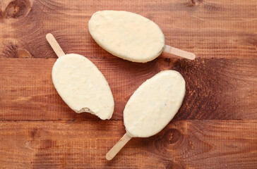 Tasty chocolate covered ice cream on wooden background