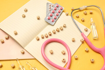 Word HORMONES with pills, ampules, notebooks and stethoscope on yellow background