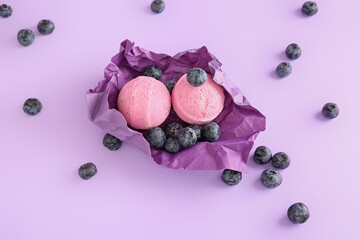 Bath bomb on crumbled paper with blueberry on lilac background