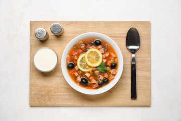 Bowl of tasty Hodgepodge soup with sour cream on light background