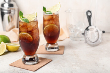 Glasses of cold Cuba Libre cocktail on light background