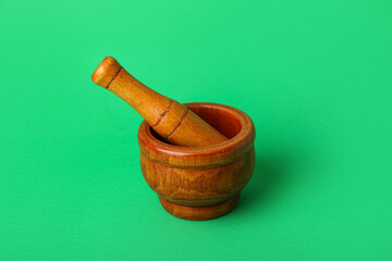 Wooden mortar and pestle on green background