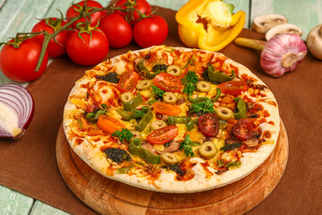 Board with vegetable pizza and ingredients on green wooden background