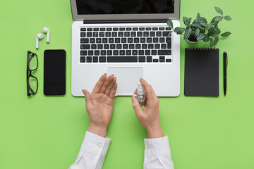 Woman applying hand sanitizer at green table in office