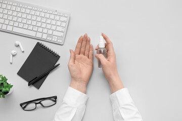 Woman applying hand sanitizer at grey table in office