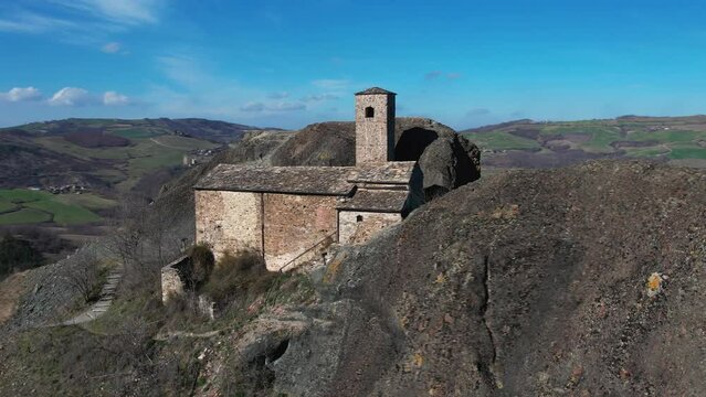 Aerial footage of Pietra Perduca, volcanic rock, church set at top stone immersed in countryside landscape, cultivated land in Val Trebbia Bobbio, Emilia Romagna, Italy