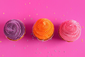 Tasty colorful cupcakes on pink background