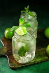 Mason jar of tasty mojito on green background