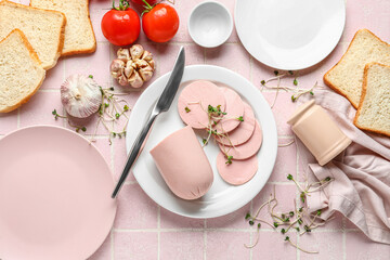 Composition with boiled sausage in plate, garlic and tomatoes on pink tile table © Pixel-Shot