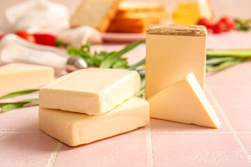 Processed cheese and herbs on pink tile background